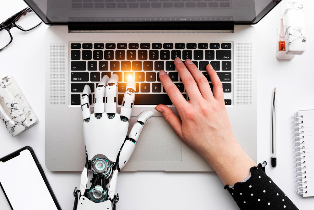 AIロボットの手と人間の手がキーボードでタイピングしている様子、AIと人間の技術の協力を象徴する画像